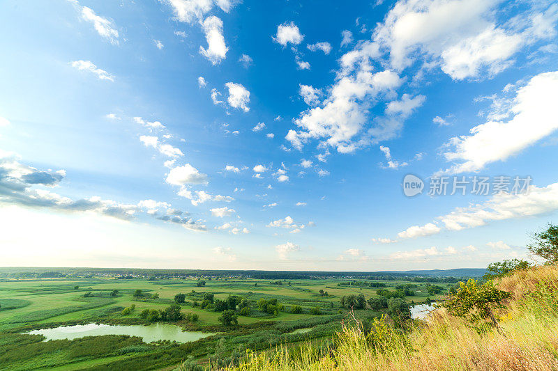 一个美丽的山谷有一条河，蓝色的天空有大云朵和明亮的太阳。空中4 k UHD